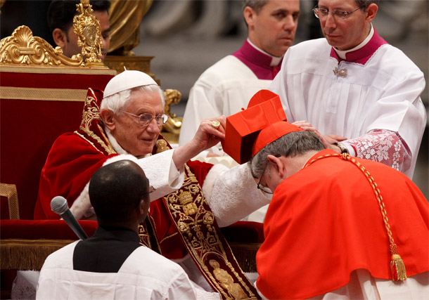 Pope Benedict XVI presents a red biretta to Cardinal Thomas C. Collins of Toronto during a consistory in St. Peter's Basilica at the Vatican Feb. 18. The pope created 22 new cardinals from 13 countries -- including two from the United States and one fro m Canada. (CNS photo/Paul Haring)