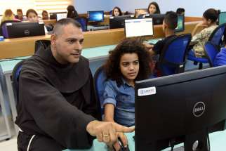 Franciscan Father Mario Hadchity sits with Sara Wajne July 18 in the computer lab at the new youth center in Jericho, West Bank.
