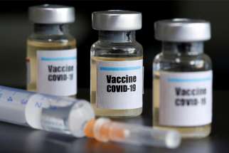 A file photo shows small bottles labeled with a &quot;Vaccine COVID-19&quot; stickers and a medical syringe.