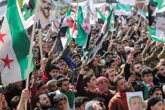 People carry banners and opposition flags during a demonstration marking the 10th anniversary of the start of the Syrian conflict, in the opposition-held city of Idlib, Syria, March 15. As Syria marks 10 years of devastating conflict, the country is in economic and social shambles with millions of people displaced and millions more living below the poverty line.