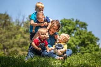 A mother plays with her triplets and other son at a park in St. Louis April 24. 