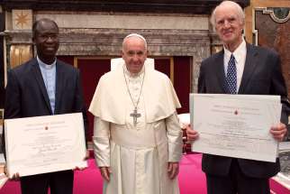 Pope Francis poses for a photo with Jesuit Fr. Paul Bere, left, and philosopher Charles Taylor, winners of the Ratzinger Prize, during a ceremony at the Vatican Nov. 9.