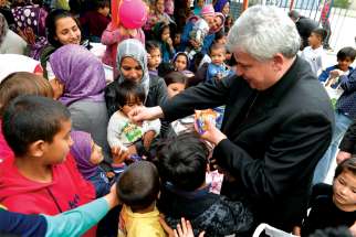 Cardinal Konrad Krajewski gives candy to children as he visits the Hope and Peace Center for refugees on the Greek island of Lesbos.