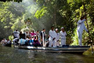 A priest holds a Bible as he leads pilgrims in prayer along during an annual river procession and pilgrimage on the Caraparu River in Santa Izabel do Para, Brazil, in this 2012 file photo.