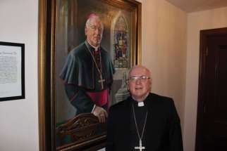 Outgoing Ottawa-Cornwall Archbishop Terrence Prendergast stands beside a portrait of himself.