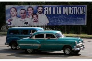 Cars in Havana drive past a banner Dec. 17 featuring five Cuban prisoners held in U.S. custody; two were previously released. U.S. President Barack Obama announced a shift in policy toward Cuba Dec. 17.