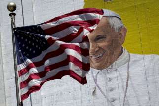 The U.S. flag flies in front of a mural of Pope Francis in New York City. Pope Francis’ 10th foreign trip will be the longest of his pontificate and, with stops in Cuba, three U.S. cities and the United Nations, it also will be a “very complex trip,” the papal spokesman said.