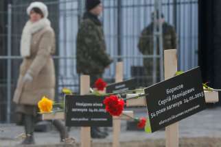 Ukrainians walk past symbolic crosses set up by protesters in front of the Russian embassy in Kiev, Ukraine, Feb. 1.
