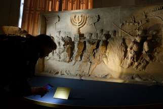 A journalist looks at a replica of the 1st-century Arch of Titus, showing Roman soldiers carrying the menorah, in a exhibition at the Vatican May 15. The replica is the central motif in a two-part exhibition on the menorah at the Vatican and at the Jewish Museum in Rome.