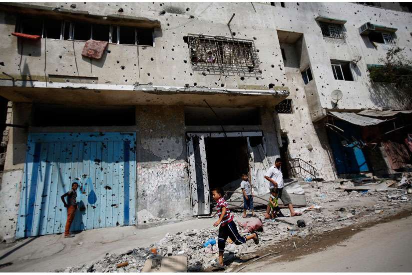 A Palestinian boy runs next to destroyed buildings in Gaza City Aug. 28. The destruction came amid the latest fighting between Israel and Hamas, and with the present blockade in place, few see any chance for reconstruction. 