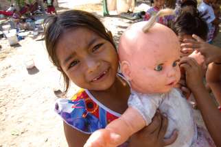 A girl at an informal refugee camp set up by Indigenous Venezuelans shows off her doll. 