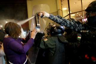 Riot police in La Paz, Bolivia, spray protesters with pepper spray Oct. 21, 2019.