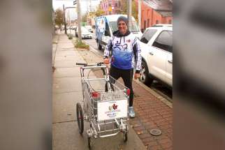 Joe Roberts behind the shopping cart he is pushing from coast-to-coast to raise awareness of youth homelessness in Canada.