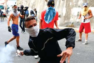 A demonstrator throws back a tear gas canister while clashing with the Venezuelan National Guard Jan. 21 during a protest close to one of their outposts in Caracas. 