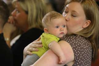A mother kisses her 3-month-old son during Mass in Huntingtown, Md., May 3. An Italian priest is offering more than $2,000 to Catholic couples who have three or more children under certain conditions.