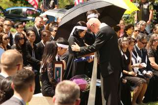 Msgr. Richard Paperini comforts Myhanh Best, wife of Ricky Best, who was killed on a Portland, Ore., commuter train May 26 while defending two girls from an anti-Muslim racist attack. The ceremony was held June 5 at Willamette National Cemetery in Portland, following a funeral Mass for Ricky Best at Christ the King Church in Milwaukie, Ore.