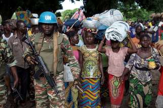 A U.N. peacekeeping soldier guards women fleeing Zike, Central African Republic, as they arrive April 26 in the village of Bambara.