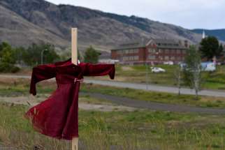 A child’s red dress hangs on a stake near the grounds of the former Kamloops Indian Residential School June 6, 2021. 