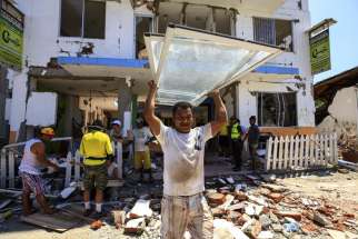 Residents recover some of their belongings April 25 from debris of a destroyed building in Canoa, Ecuador. Catholic agencies will begin building temporary shelters for thousands of families displaced by the April 16 magnitude-7.8 earthquake, the country&#039;s worst natural disaster in nearly seven decades.