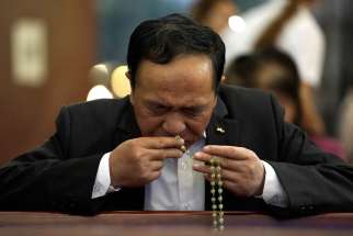 A man kisses a rosary as he prays before Mass in 2018 at a church in Beijing. The Day of Prayer for Catholics in China is celebrated annually May 24.