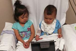 Timothy Rafanan with his sister Emily playing with an iPad as he receives his regular blood transfusion.