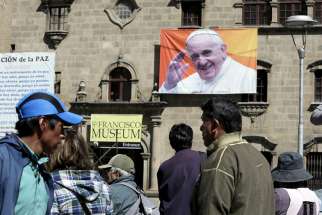 People walk past an image of Pope Francis in La Paz, Bolivia, June 30. The Pope will visit Bolivia July 8-10.