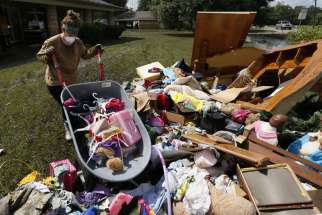 Melissa Gouda removes flood damaged items out of a friend&#039;s house in St. Amant, La., Aug. 21. Historic flooding in southern Louisiana killed at least 13 people and damaged an estimated 60,000 homes, said state officials. At least 102,000 people have registered for federal recovery assistance.