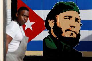 An employee of a state-owned candy store looks outside near a painting depicting Cuba&#039;s former President Fidel Castro, following the announcement of Castro&#039;s death, in Havana, Nov. 27.