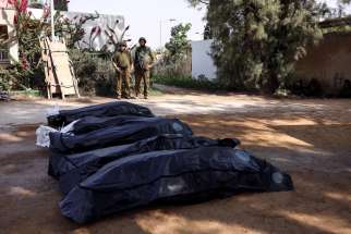 Israeli soldiers stand guard over bodies in Kfar Aza, a kibbutz in southern Israel, Oct. 10, 2023. Former Israeli prime minister Naftali Bennett told an Ottawa audience April 12 Israel must prevail in its fight with Hamas or the spread of terror could reach foreign shores like Canada and the United States.