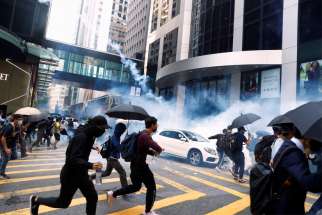 People in Hong Kong run from riot police tear gas Nov. 11, 2019.