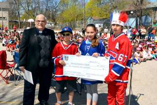Fr. Larry Marcille, pastor of Blessed Sacrament parish in Toronto, is presented with a cheque for $3,000 by students from Blessed Sacrament School. The money is to be donated to the Family of Faith campaign.