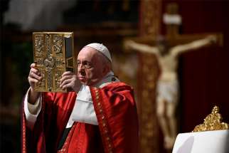 Pope Francis raises the Book of the Gospels as he celebrates Pentecost Mass in St. Peter&#039;s Basilica at the Vatican May 31, 2020.