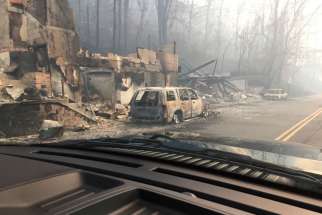 Burned buildings and cars are seen Dec. 1 in Gatlinburg, Tenn., in the aftermath of wildfires. Raging wildfires fueled by high winds claimed the lives of at least seven people, forced the evacuation of thousands, including Father Antony Punnackal of St. Mary&#039;s Church, and damaged hundreds of buildings in the popular mountain resort town.