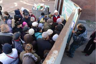 People displaced by fighting in Eastern Ukraine wait to enter an abandoned building site in Kiev, Oct. 19. The lot has been turned into a center for the distribution of food, clothing and other aid. 