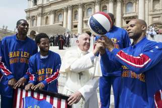 Pope Francis smiles as he plays with a basketball next to a members of the Harlem Globetrotters basketball team during his weekly audience in St. Peter&#039;s Square at the Vatican May 6. 