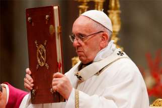Pope Francis raises the Book of the Gospels as he celebrates Christmas Eve Mass in St. Peter&#039;s Basilica at the Vatican Dec. 24. 