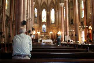 A man prays in 2013 at a church in Rio de Janeiro. Due to the swine flu outbreak in several parts of Brazil, parishes all over the country have adopted changes in liturgical practices.
