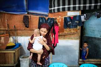 A Rohingya woman holds her 2-month-old baby in early February at a refugee shelter in Medan, Indonesia. The woman and her husband fled persecution in their village in Myanmar and have been waiting for two years to be resettled to Malaysia or Australia.