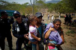 A family of Central American migrants is detained by Mexican federal police officers April 22, 2019, in Pijijiapan, Mexico, during their journey toward the United States. 