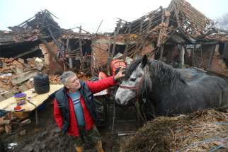  Farmer Tomislav Suknaic touches his horse in front of his destroyed home in the village of Majske Poljane, Croatia, Dec. 30, 2020, following an earthquake. Pope Francis offered condolences and prayers for the victims of the magnitude 6.4 earthquake that rocked central Croatia the previous day, killing at least seven people and injuring dozens.