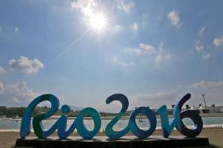 Canoe athletes preparing for the 2016 Summer Olympics paddle behind an Olympic sign Aug. 2 in Rio de Janeiro.