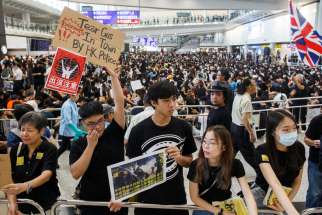 Anti-extradition bill protesters hold placards for arriving travelers during a protest at Hong Kong International Airport Aug. 9, 2019. More than 1,000 Catholics prayed during a candlelight vigil outside the Cathedral of the Immaculate Conception Aug. 8 for Hong Kong to solve its political crisis in a nonviolent manner.