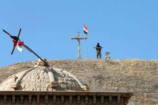 An Iraqi soldier guards St. Barbara Church Oct. 30 after it was recaptured from Islamic State militants in Qaraqosh. Similarly, in the town of Bashiqa, north of Mosul, the Mar Korkeis church was reopened after two years under Islamic State control. 