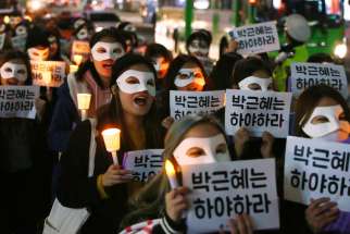 South Korean university students carry candles and placards that read &quot;Park Geun-Hye Step Down&quot; Nov. 15 in Seoul. The South Korean president is embroiled in scandal involving a longtime friend.