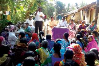 A group of  villagers in India listen to a Lok Manch speaker as he educates them on their rights under the National Food Security Act.