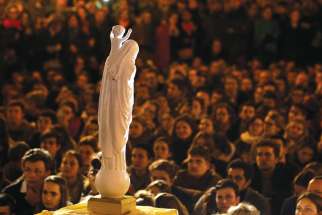 People stand in front of a statue of Our Lady of Notre Dame during a vigil near Notre-Dame Cathedral April 16, a day after a fire destroyed much of the church’s wooden structure. 