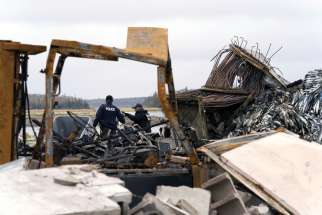 Police officers investigate the remains of a lobster pound destroyed by a fire in Middle West Pubnico, N.S., Oct. 17.