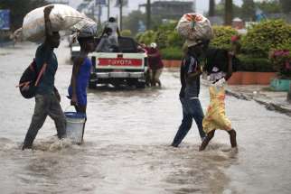 People cross a flooded street in Port-au-Prince, Haiti, Aug. 23, 2020, during the passage of Tropical Storm Laura.