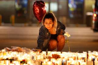  A woman lights candles at a makeshift vigil on the Las Vegas Strip Oct. 2 following a mass shooting at an outdoor country music festival. Late Oct. 1 a gunman perched in a room on the 32nd floor of a casino hotel unleashed a shower of bullets on the festival below, killing at least 59 people and wounding another 527. Three Canadians are among the dead.