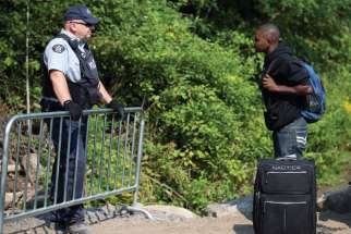 A Haitian man talks with an RCMP officer as he waits to cross the U.S.-Canada border into Quebec last summer. 